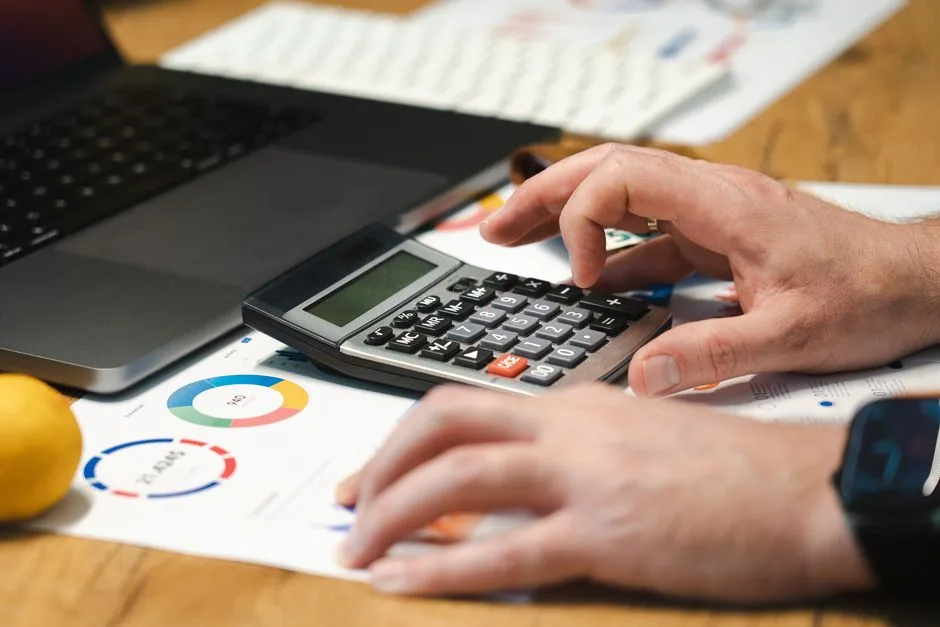Mains sur une calculatrice, tableau de bord imprimé à côté